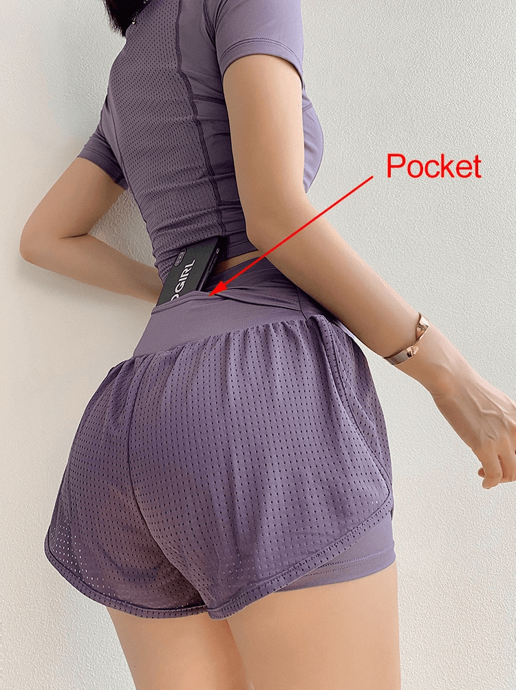 Woman wearing breathable mesh sports shorts with high waist and showing secret back pocket with a phone inside.